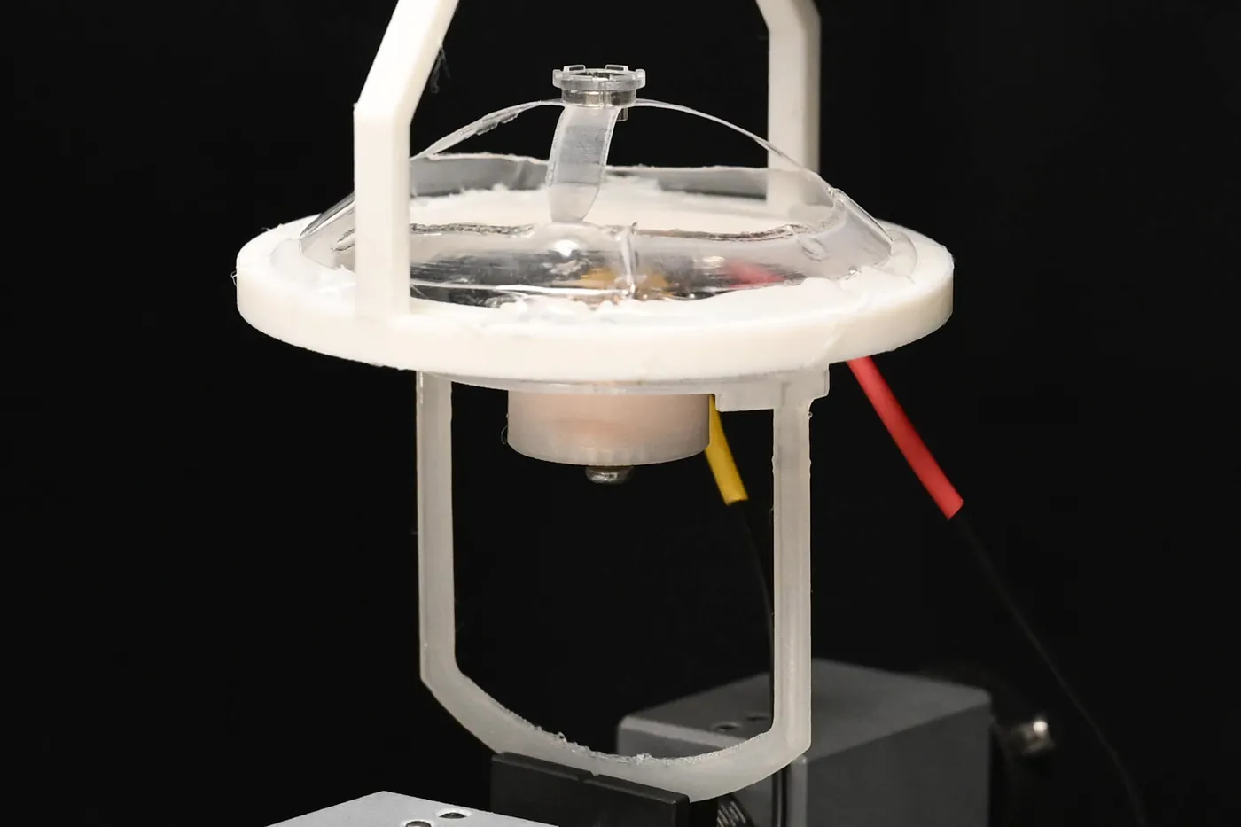 A single transparent BEAMbot cell mounted in a white test fixture above a coil