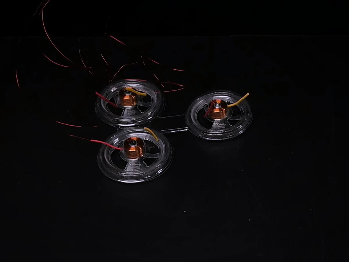 Three BEAMbot modules turning on a black surface, seen from above